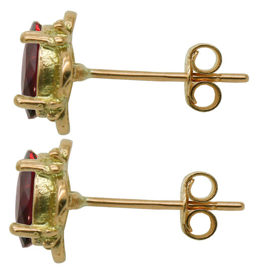 Gold earrings with red garnet gemstones on a white background